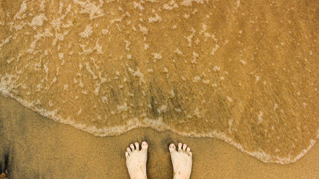 Füße vor einer kleinen Welle