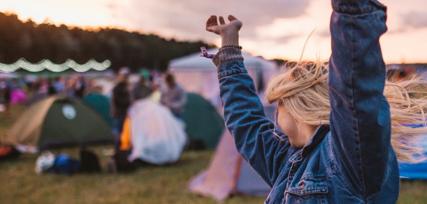 Eine junge Frau tanzt vor ein paar Zelten