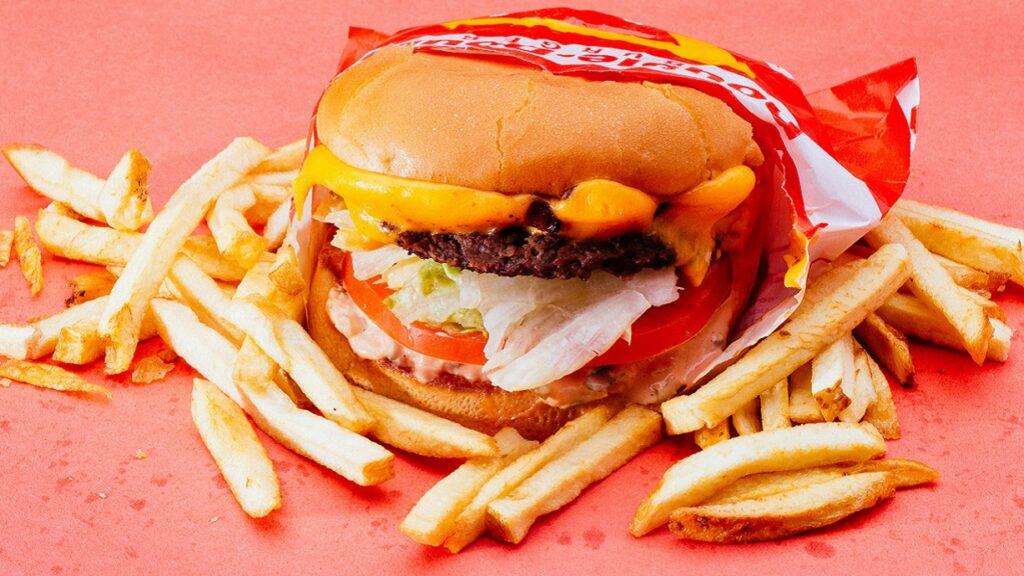 Ein Burger und Pommes Frites auf einem roten Untergrund.