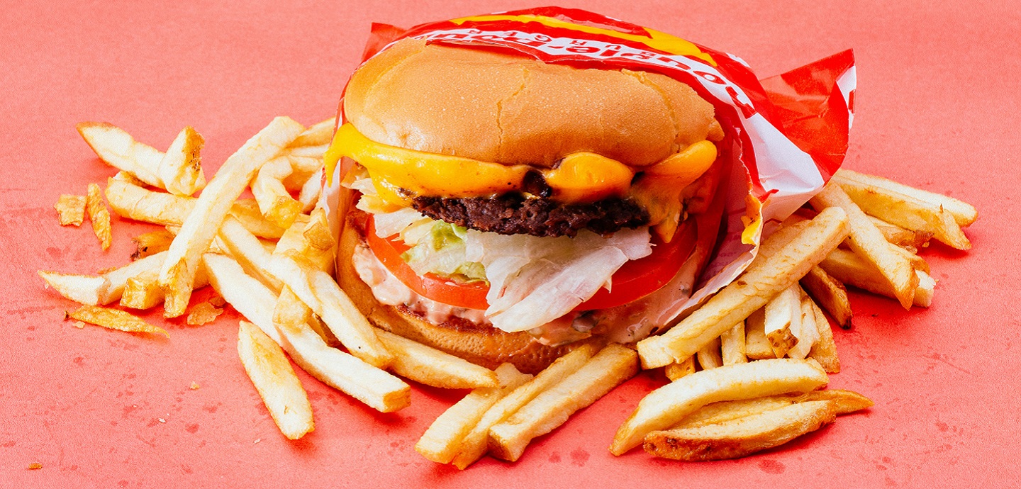 Ein Burger und Pommes Frites auf einem roten Untergrund.