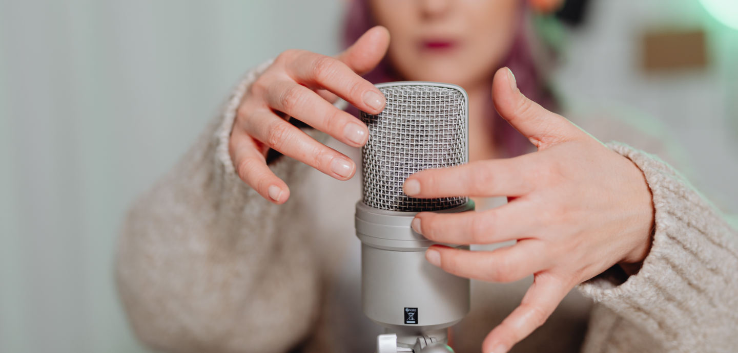 Eine Frau tippt mit ihren Fingern auf ein Mikrofon.