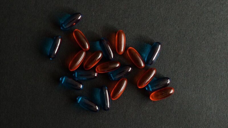 Rote und blaue Pillen vor schwarzem Hintergrund