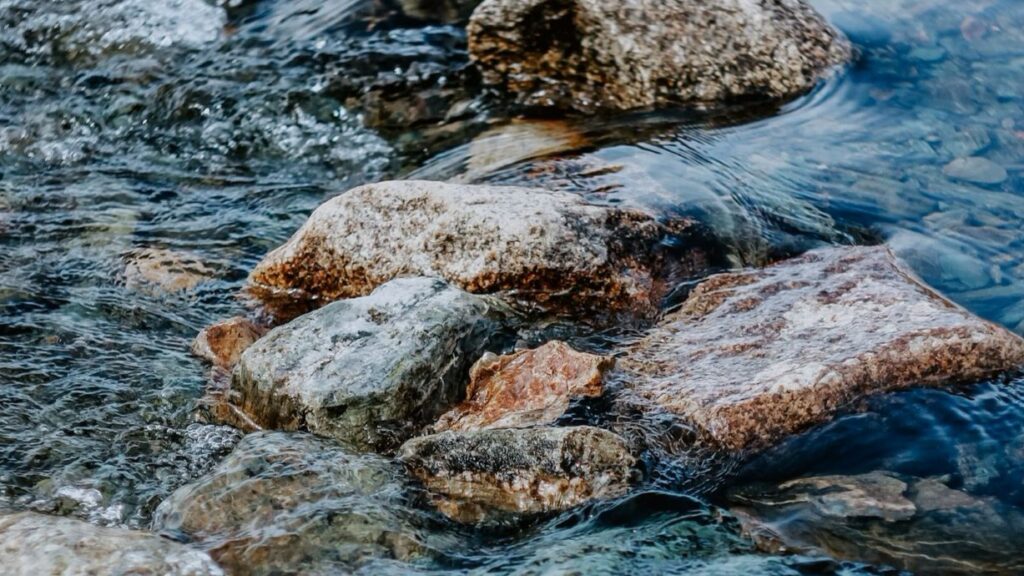 bunte Steine in seichtem Gewässer eines Süßwasserflusses.